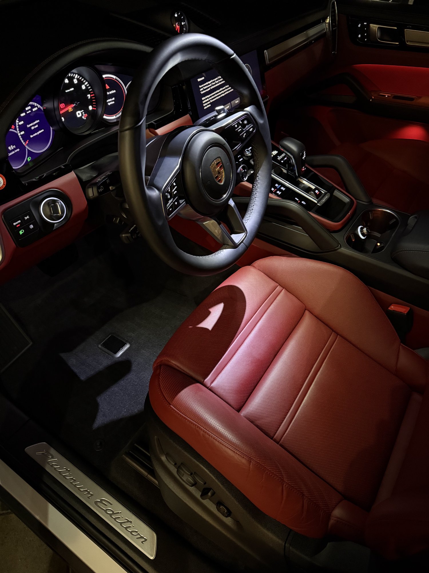 Porsche Macan Platinum Edition interior detail — red leather steering wheel and dash